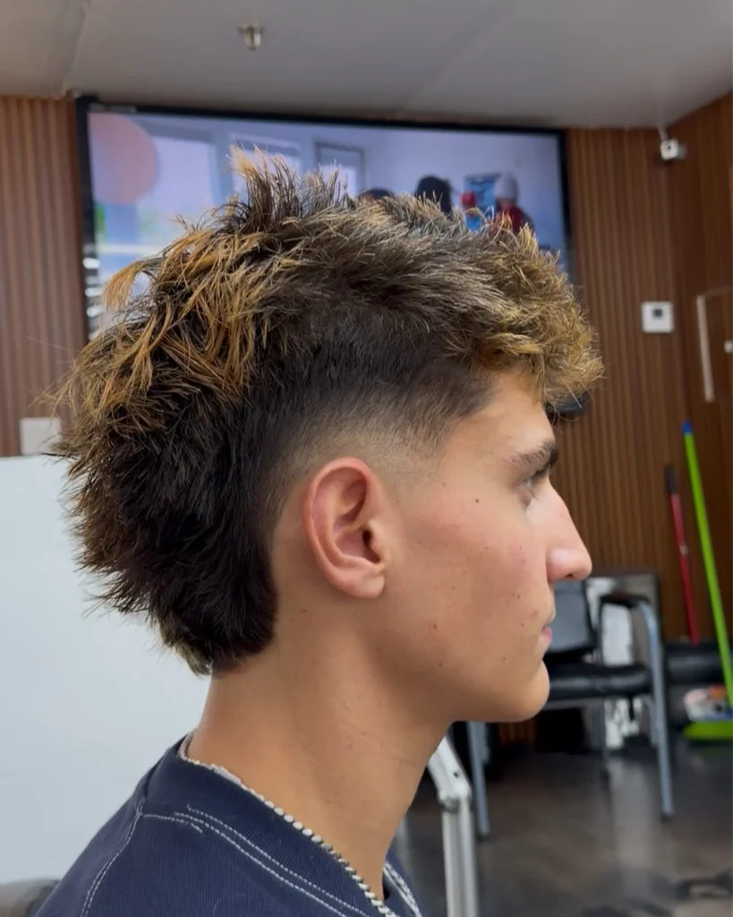 Textured mullet with caramel highlights and a low burst fade, cut by Leo Sanchez