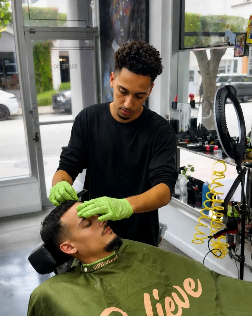 Barber Leo Sanchez detailing a client's hairline with a trimmer at Alchemy Hair Lab