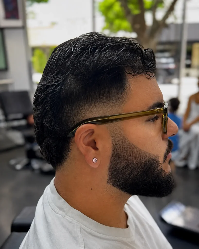 Low taper fade with a sculpted full beard and sharp cheek line by Leo Sanchez