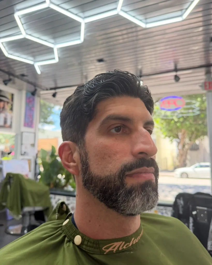 Slicked-back style with comb waves and a shaped salt-and-pepper beard by Leo Sanchez