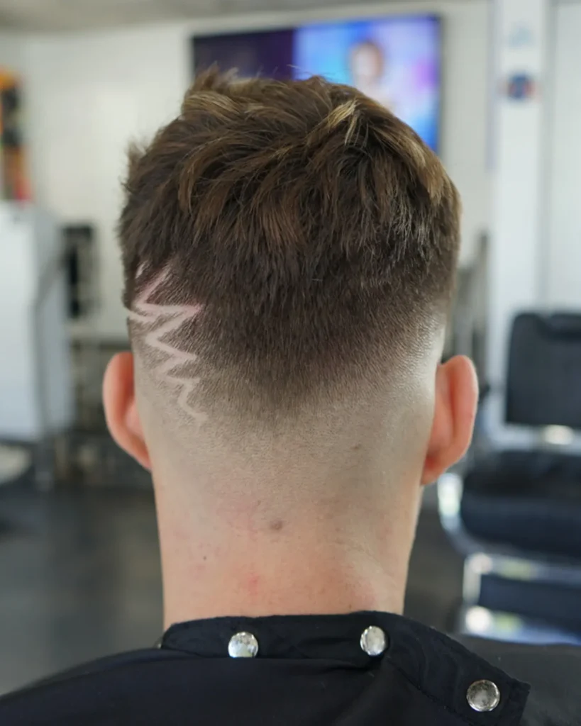Back view of a skin fade with a carved lightning design, cut by Luis Mosquera