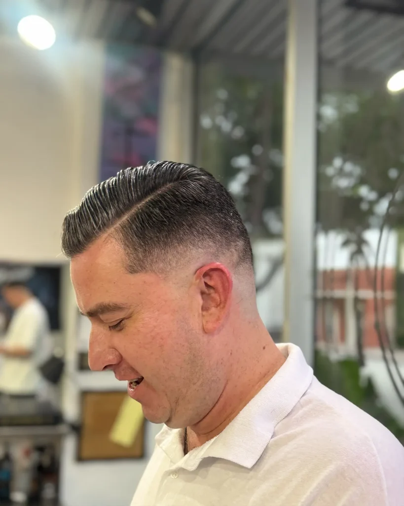 Slicked side part with a razored hard part and skin fade, cut by Luis Mosquera