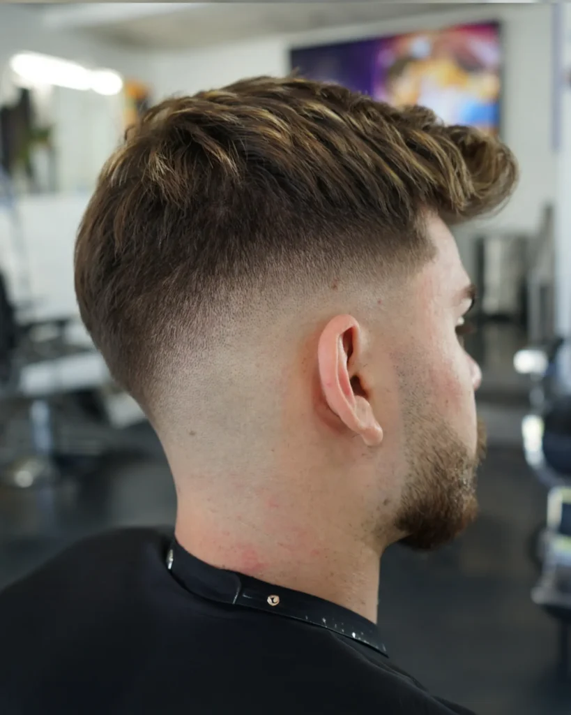 Caramel-highlighted quiff blended into a clean skin fade by Luis Mosquera