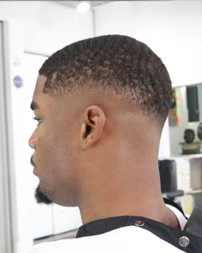 Sharp lineup and low taper fade on natural coily hair at Alchemy Hair Lab
