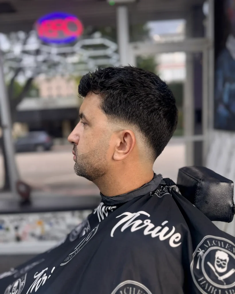 Low taper fade in an Alchemy Hair Lab cape, cut by Luis Mosquera
