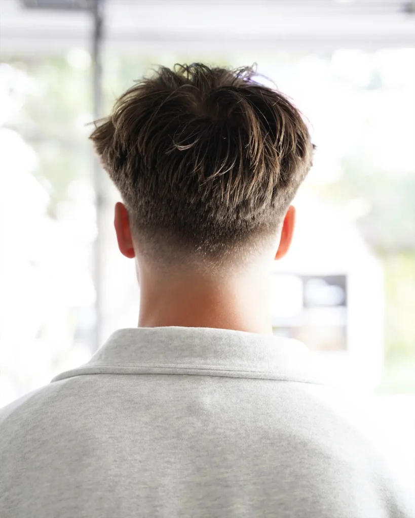 Back view of a low taper fade blending into the neckline, cut by Luis Mosquera